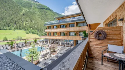 PAZNAUN TOUR © Stephanie Maria Lohmann Balcony overlooking pool and wooden building in mountains on sunny day