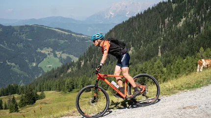 Frauenalm-Jägersee Tour Cyclist rides on mountain path with mountains in background