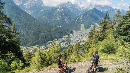 Julian Alps © Grega Teraz Two mountain bikers on forest trail overlooking valley and mountains