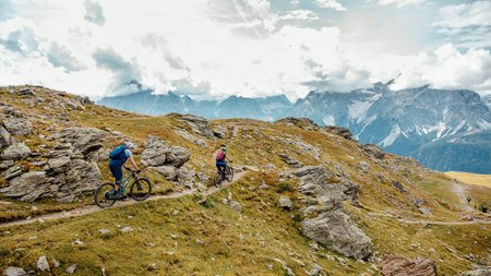 Quality Promise © David Karg Two mountain bikers riding on a rocky mountain trail under cloudy sky