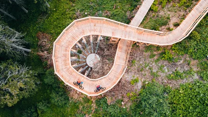 Sun Rest Trail © Patrick Wasshuber Cyclists on spiral wooden bridge in green forest
