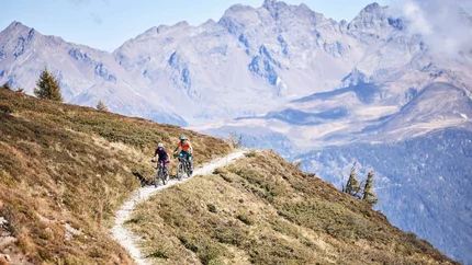 Dragon Trail © Tobias Köhler Two cyclists riding on mountain trail with Alps in background
