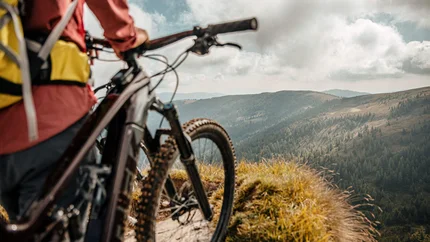Geweldig uitzicht - rondreis vanuit Obermillstatt © Felix Saller Mountainbiker kijkt uit over beboste heuvels onder een bewolkte hemel