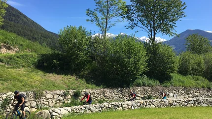 Tour around Pfalzen © Hotel Innerhofer Four cyclists biking on a path beside a stone wall in the mountains