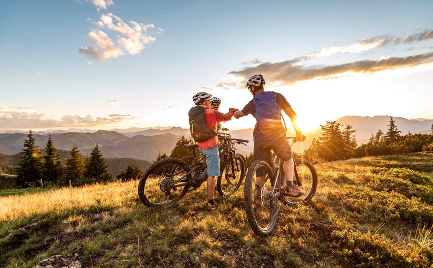 Mountain biking in Salzburger Land © TVB Flachau - Ulrich Grill Two mountain bikers greeting at sunset on a mountain trail