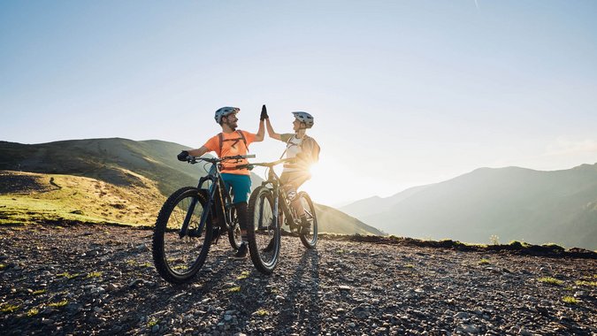 Mountain Bike Holidays © Tobias Köhler Zwei Radfahrer geben sich beim Mountainbiken in den Bergen einen Highfive
