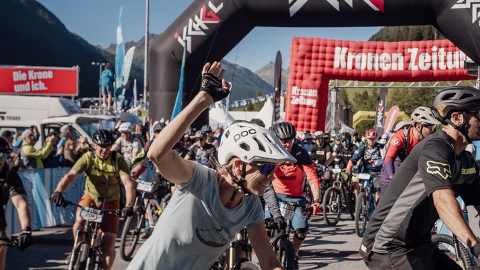 Start E-Bike WM für Jedermann Fahrradfahrer starten bei einem Radrennen unter einem Ischgl-Bogen bei Sonnenschein