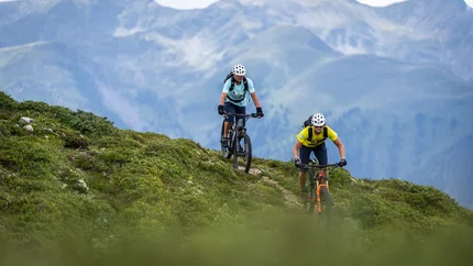 Roner Hut Tour © Hotel Jonathan Two mountain bikers riding on a trail with alpine mountains in the background