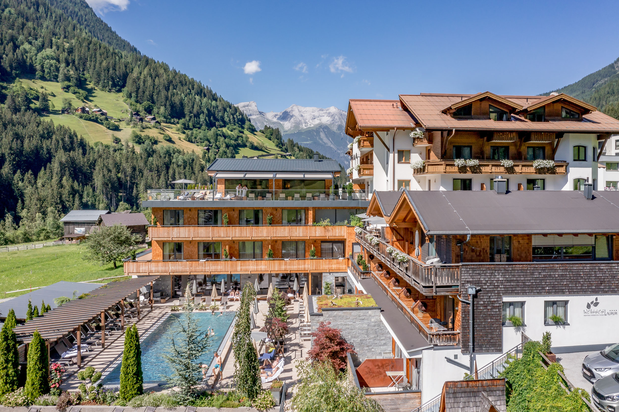 Hotel Weisses Lamm © Stephanie Maria Lohmann Modernes Hotel in den Bergen mit Außenpool und Terrasse bei sonnigem Wetter