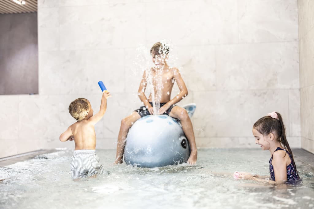 familyvacation Children playing in pool with water toy and splashing water