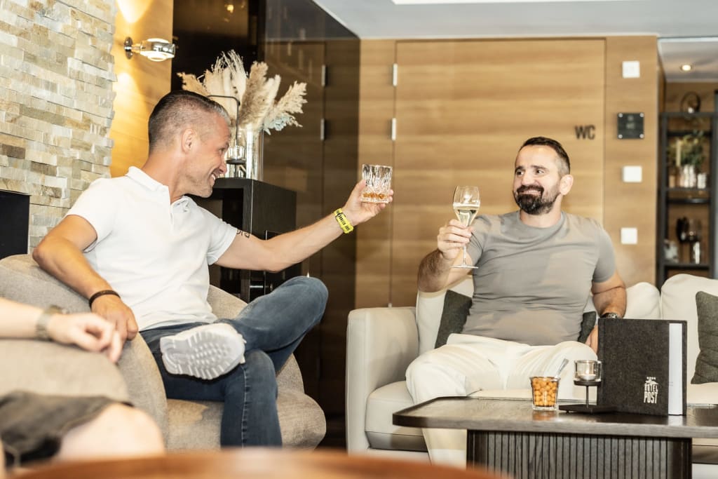 mountainbike week Two men clinking drinks in a cozy lounge
